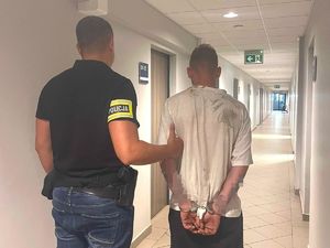 policjant trzyma za ramię zatrzymanego meżczyznę