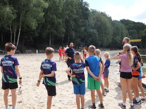 policjant na plaży edukuje młodzież na temat bezpiecznego wypoczynku nad wodą