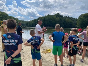 policjant i ratownik wodny prowadzą spotkanie profilaktyczne na plaży