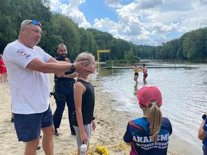 policjant i ratownik wodny prowadzą spotkanie profilaktyczne na plaży
