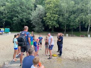 policjant i ratownik wodny prowadzą spotkanie profilaktyczne na plaży