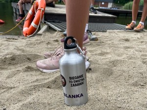 na plaży obok koła ratowniczego stoi bidon z wodą