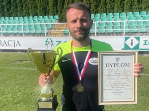 policjant pozuje do zdjęcia, trzyma dyplom i puchar
