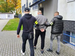policjanci prowadzą zatrzymanego mężczyznę