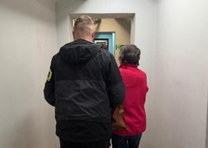 policjant stoi obok zatrzymanej kobiety